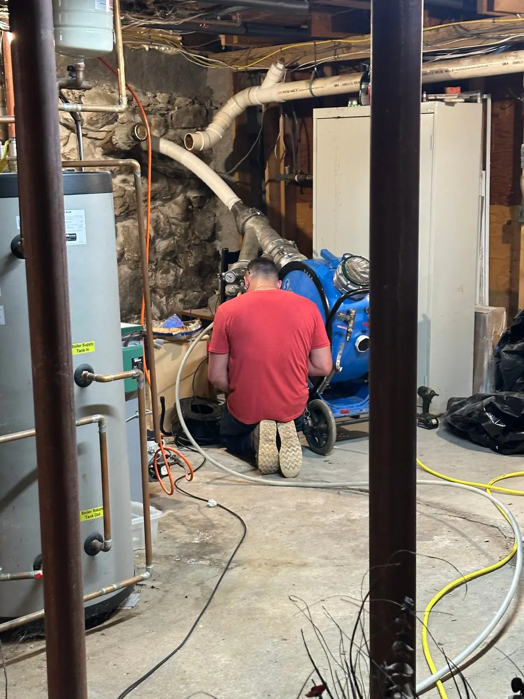 Our technician kneeling at the inversion drum in a basement on our Back Bay job