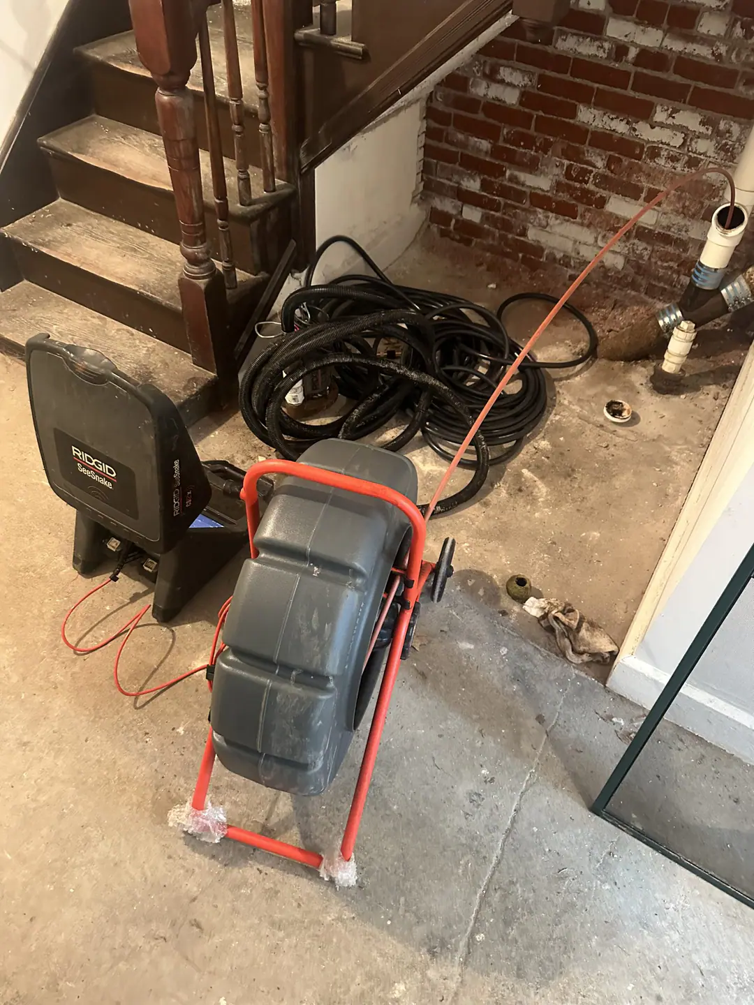Camera cable entering a basement cleanout beside the stairs on our South Boston job