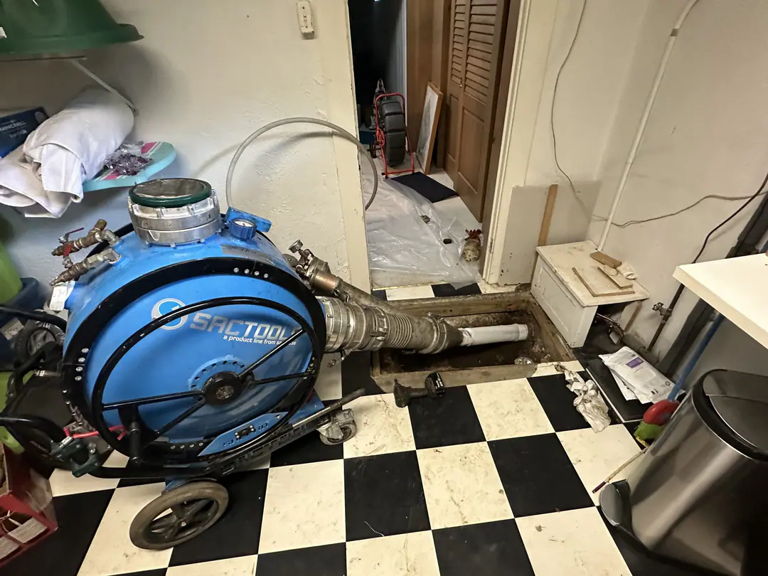 Liner inversion drum connected to the sewer through an opening in a tiled basement floor in Charlestown