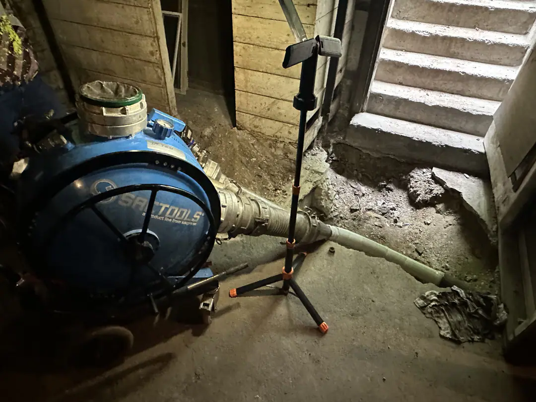 Inversion drum feeding a liner through a basement floor opening beside stairs in Dorchester