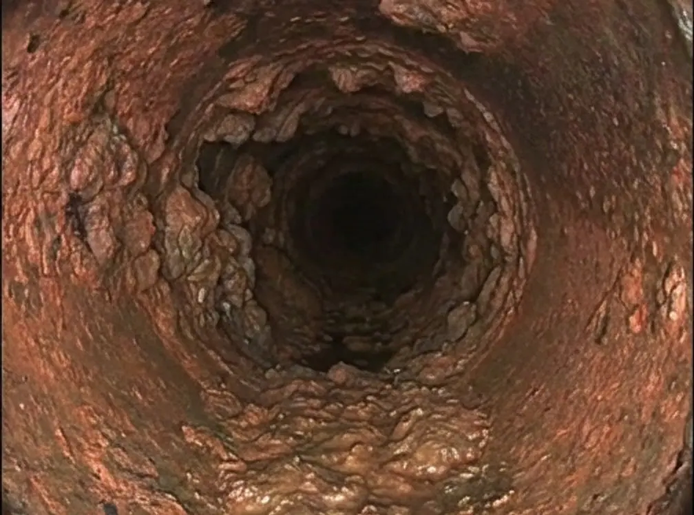 Rendering of a camera view down a cast iron pipe crusted with rust nodules